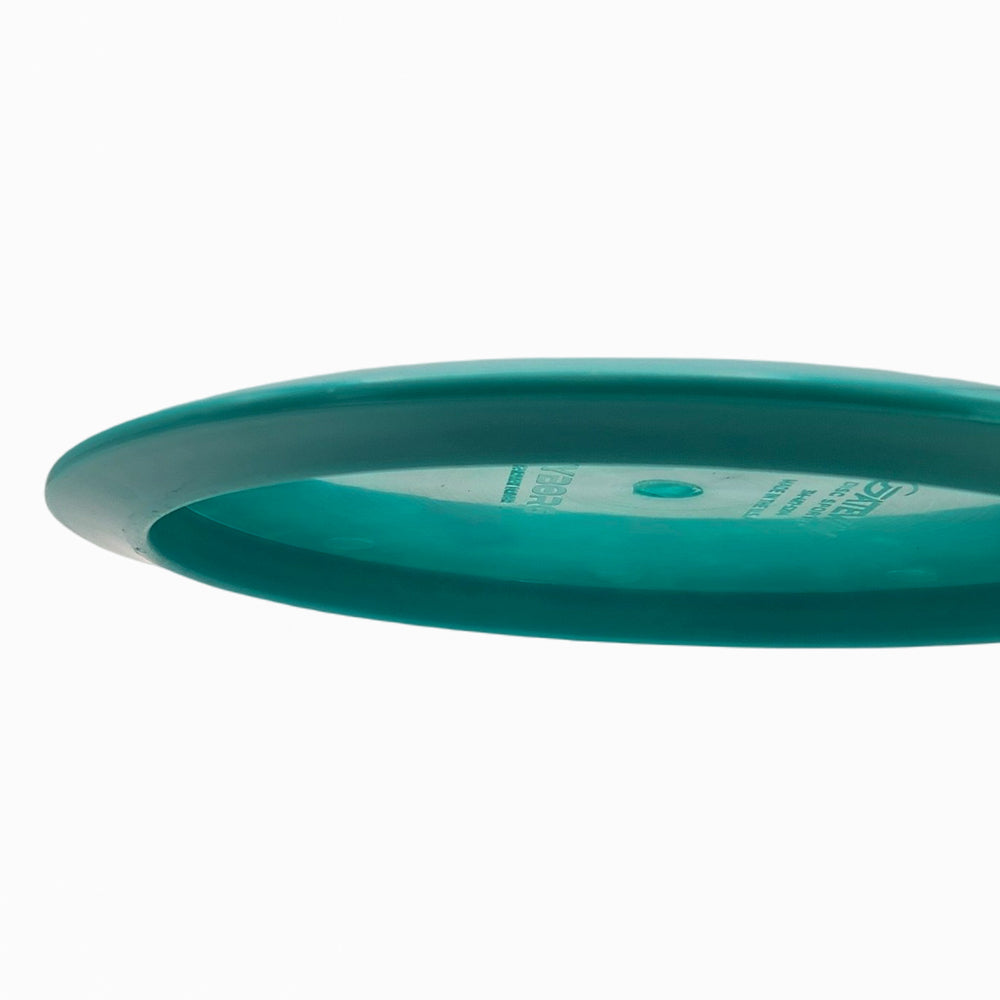 A side view of the Cyborg - NXT fairway driver disc in teal, displayed against a plain white background.
