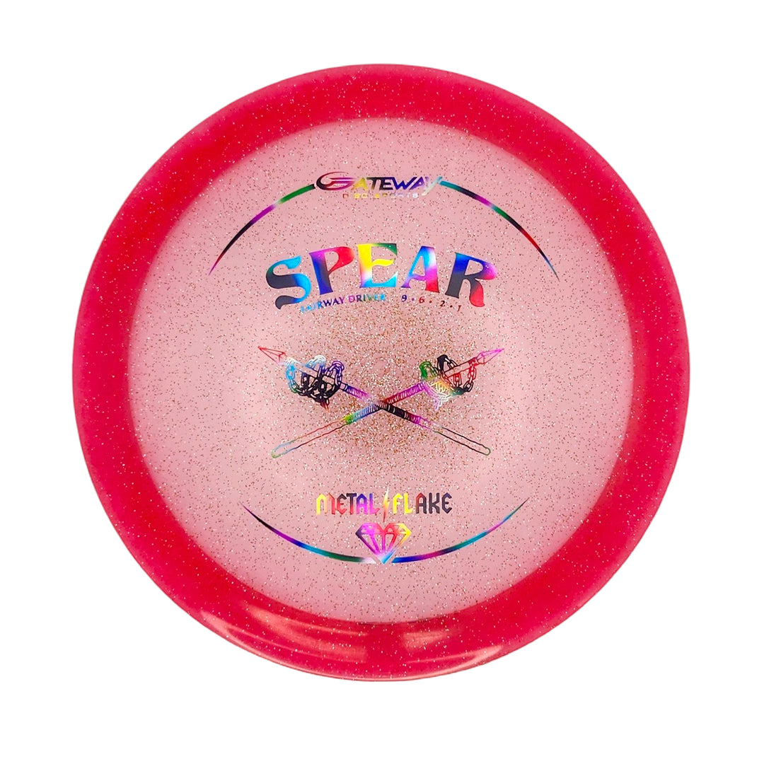 The Spear - Diamond (Metal Flake) is a pink, glittery 9-speed disc golf driver featuring crossed spears and "Metal Flake" on the front—a stylish straight driver designed for control.