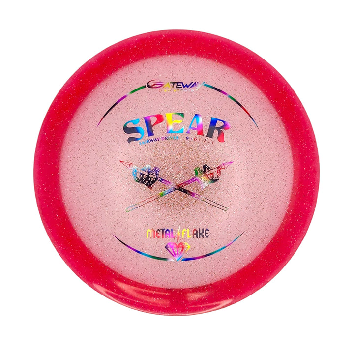 The Spear - Diamond (Metal Flake) is a pink, glittery 9-speed disc golf driver featuring crossed spears and "Metal Flake" on the front—a stylish straight driver designed for control.