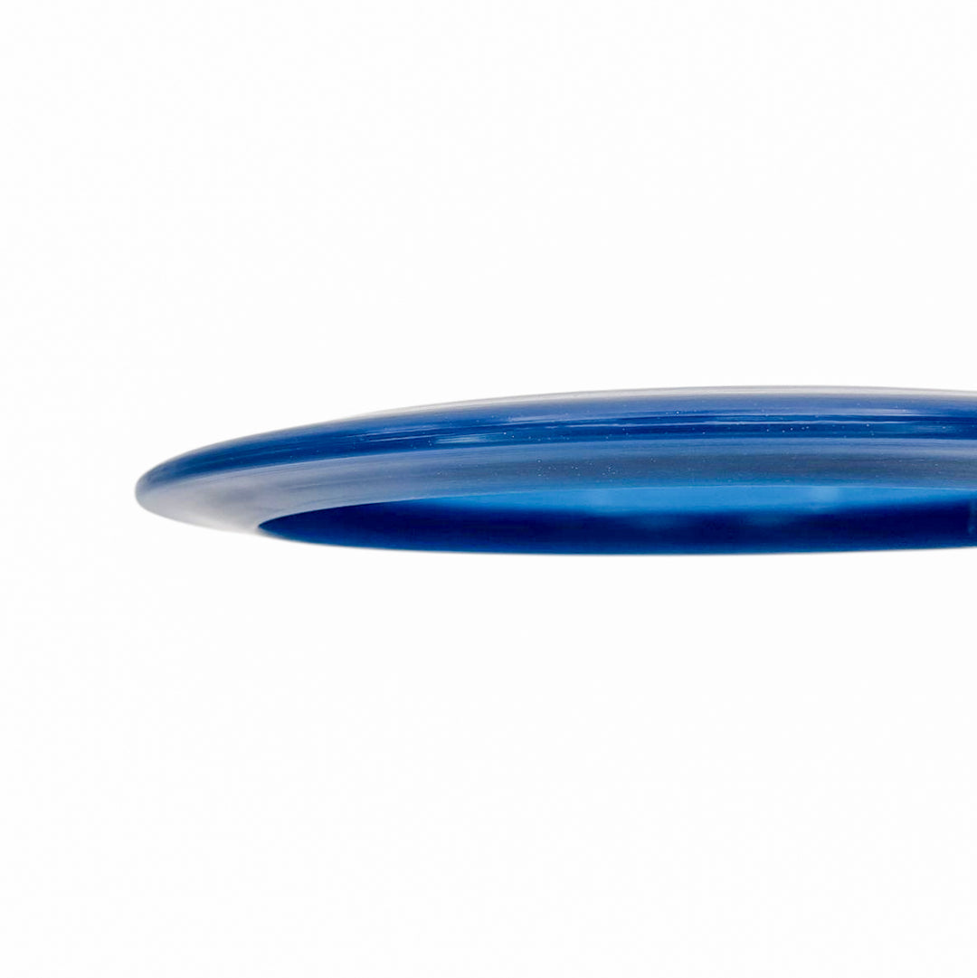 Close-up of the edge of the Realm - Diamond - Air Dude blue plastic max distance driver against a white background.