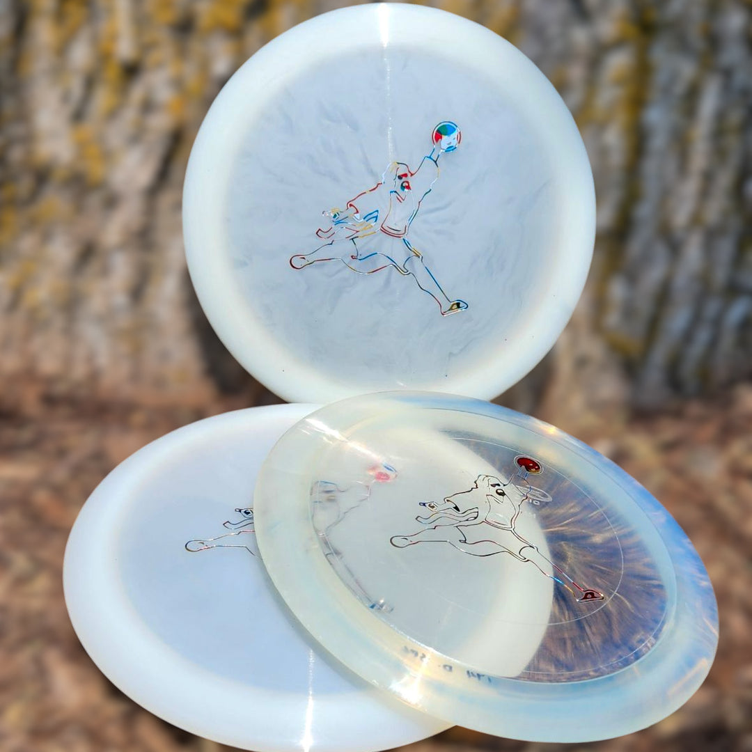 Three Spell - Diamond - Air Dude overstable driver discs in translucent white, each with an outline of a running person, are shown outdoors against blurred tree bark—perfect for wind-crushing power throws.
