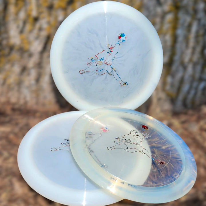 Three Spell - Diamond - Air Dude overstable driver discs in translucent white, each with an outline of a running person, are shown outdoors against blurred tree bark—perfect for wind-crushing power throws.