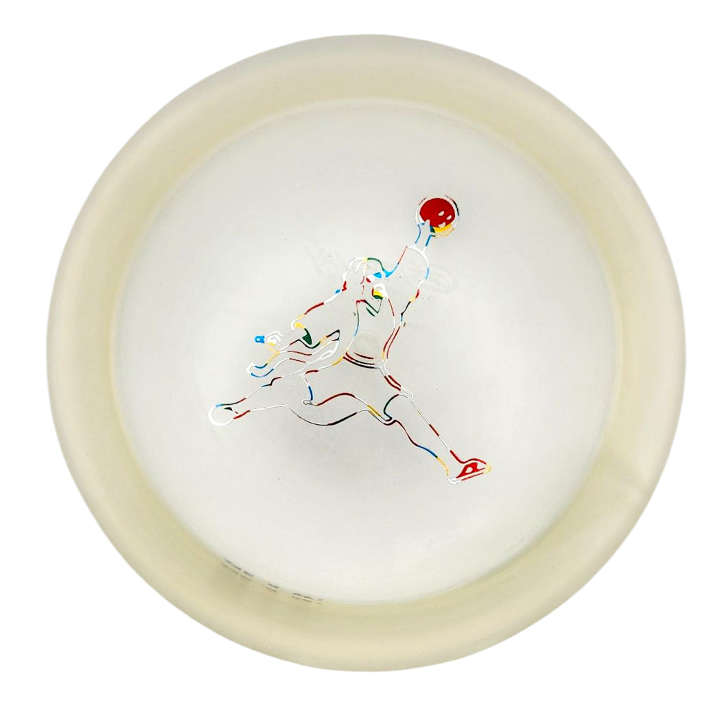 The Spell - Diamond - Air Dude is a translucent white, high-grade TPU disc with an outline of a person midair holding a red ball—ideal for powerful, wind-crushing throws.
