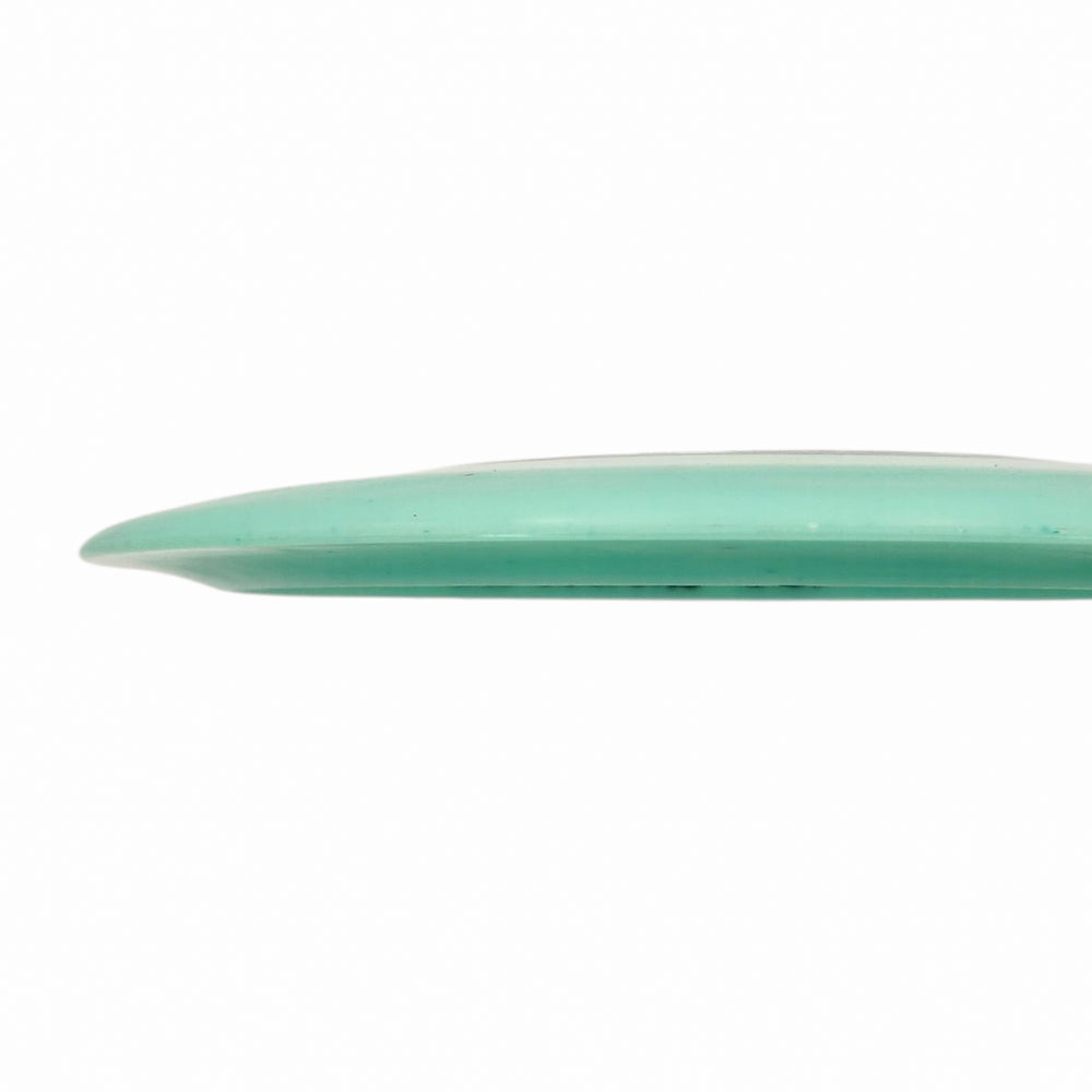A close-up side view of a green surfboard with a rounded nose and a glossy Spell NXT Superglow - PremierJul finish, set against a white background.
