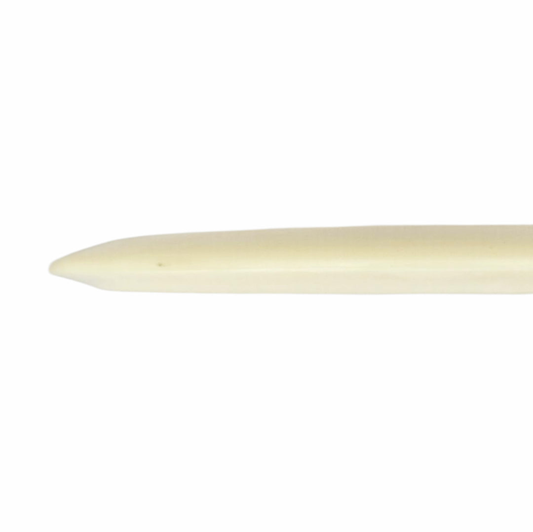 A close-up of the pointed end of a bone folder, an ivory tool for bookbinding, mirrors the precision found in Cyborg Superglow - PremierJUL mechanics.