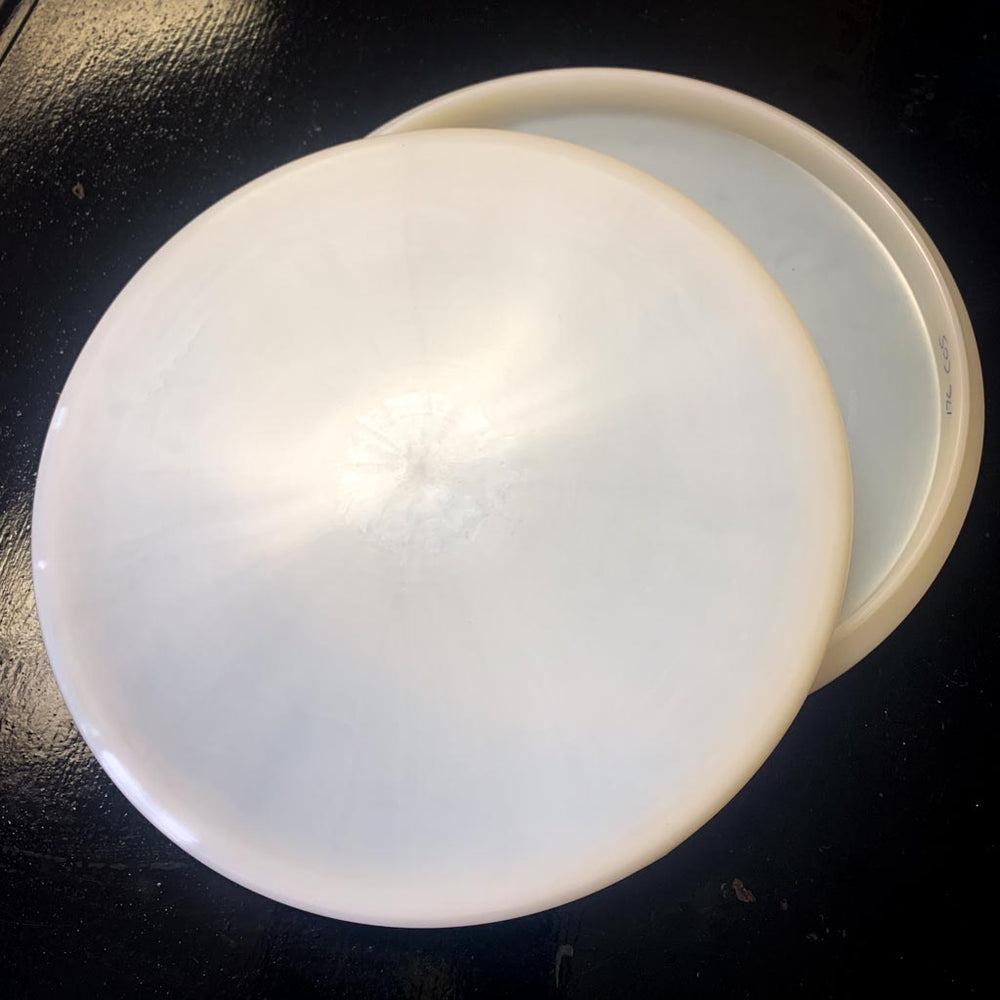 Two overlapping Dye Canvas Chief OS disc golf putters, crafted from premium plastic, rest on a dark, reflective surface.