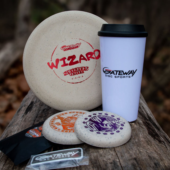 The Coffee Wizard & Mug Set includes three speckled Gateway disc golf discs, a white Gateway Wizard Coffee travel mug, a sticker, and a black packet—perfect for disc golf fans. Get yours while supplies last!.