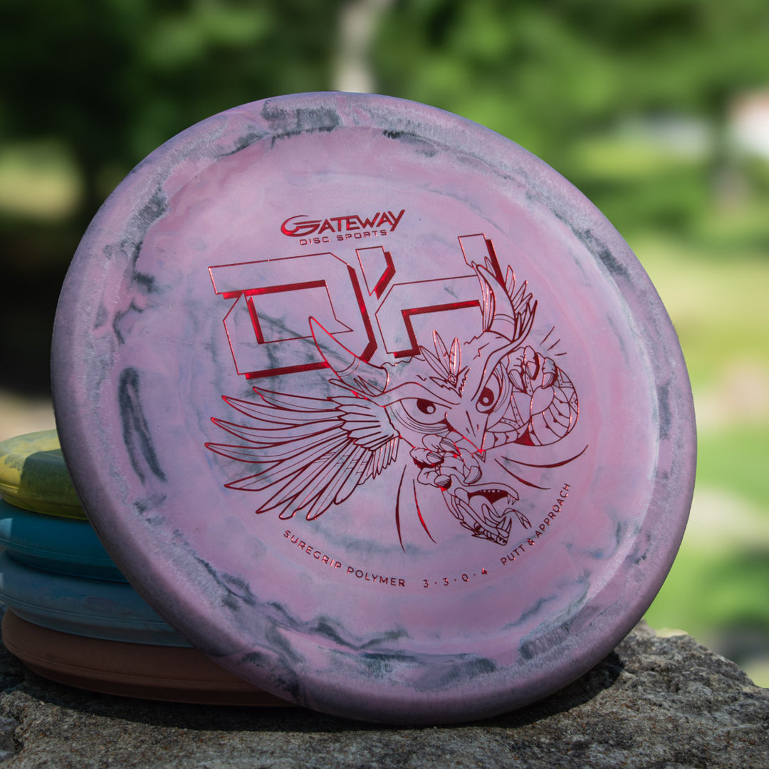 A pink and grey marbled Devilhawk - SureGrip™ Swirly Special Edition putter with an owl graphic and "Gateway Disc Sports" logo rests on stone, ready for your next overstable approach shot.
