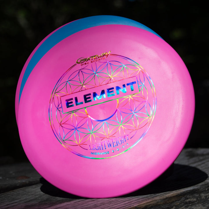 The Element Lightweight - SureGrip™  disc features pink and blue tones, metallic "ELEMENT" lettering, and geometric designs on a wooden surface—ideal for players who want outstanding glide and a straight, reliable flight.