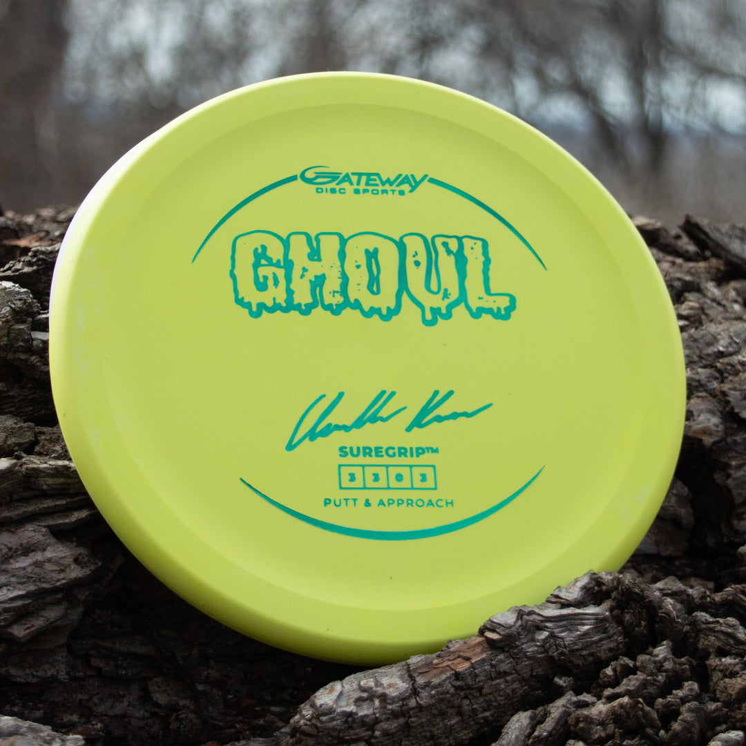 A yellow Ghoul - Chandler Kramer Signature Series disc from Gateway Disc Sports rests on rough tree bark outdoors, poised to deliver reliable flight and control for your next approach shot.