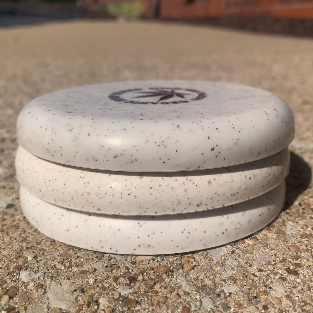 Three stacked Mini (Large) - Hemp discs with a logo on top, shown outdoors on a textured concrete surface.