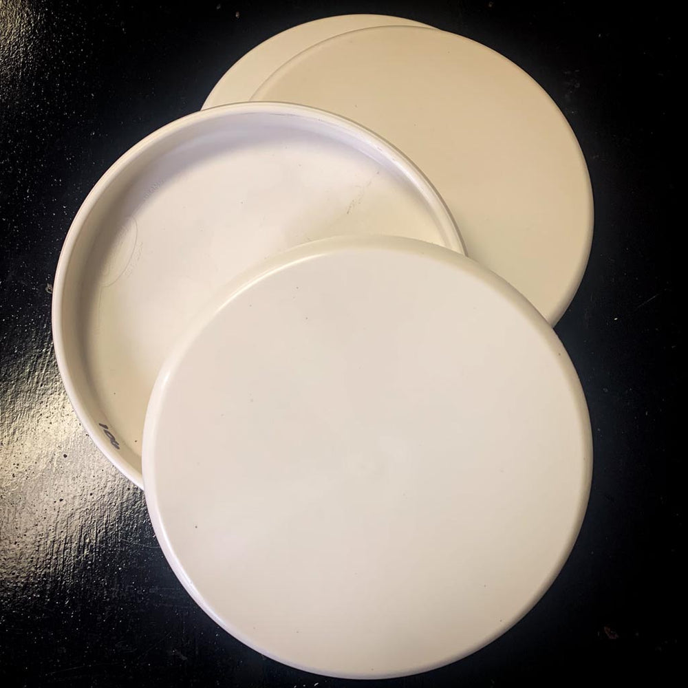Three round, white Dye Canvas - Lil Wizard - Diamond premium plastic lids are stacked and slightly overlapped on a dark surface, ideal for storing your dye accessories.