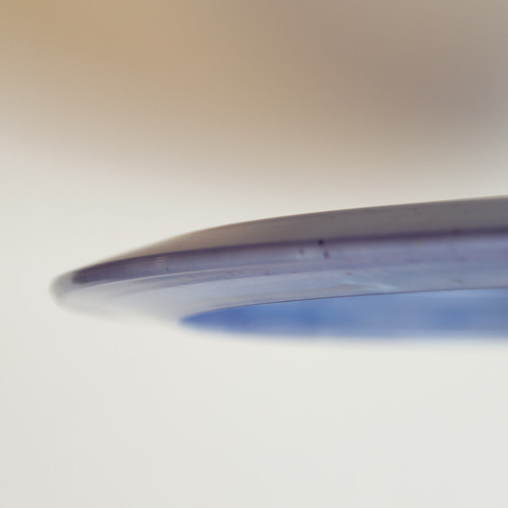 Close-up of the edge of Nina Guerrero's Aura - Diamond Metal Flake disc, highlighting its possible turnover ability against a softly blurred background.