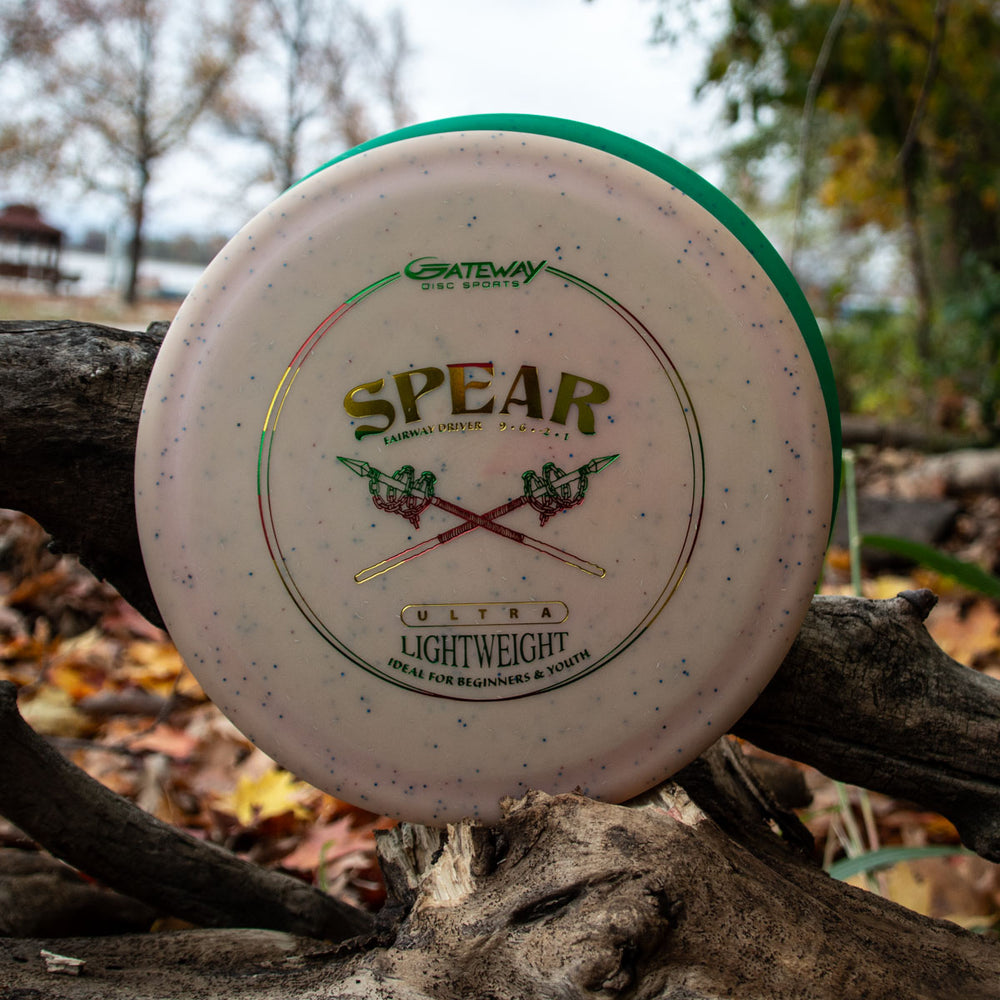 A Spear - (Metal Flake) Ultra Lightweight control driver leans against a tree branch outdoors amid fallen leaves—ideal for precise placement shots on the course.