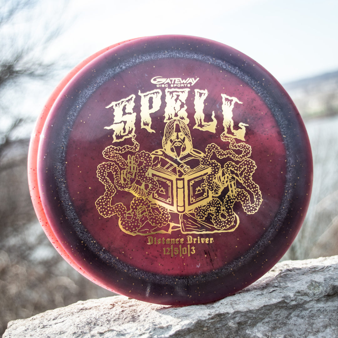 The Spell - Metal Flake - Ripper Studios is a premium red and black marbled distance driver, featuring a gold wizard holding a book—ideal for anyone seeking Gateway's longest flying disc.