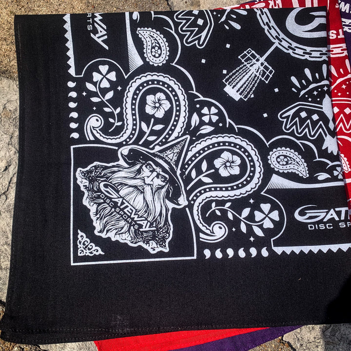 Gateway Bandana: Black cotton bandana with white illustrations of a wizard, Gateway logos, paisley designs, flowers, and disc golf-themed graphics.