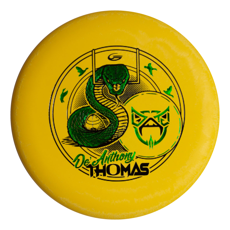 The De'Anthony Thomas' Wizard - SS is a yellow disc golf disc with a green Black Mamba-style snake, an abstract owl face, and "De'Anthony Thomas" in stylized lettering.