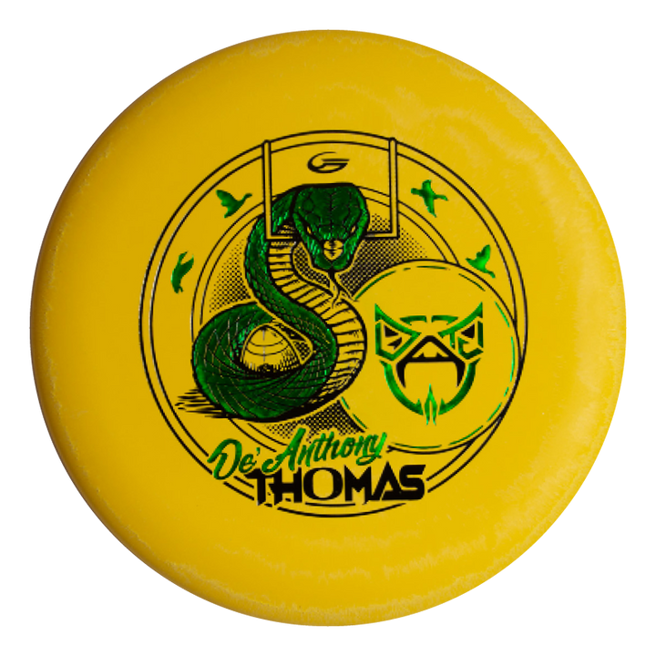 The De'Anthony Thomas' Wizard - SS is a yellow disc golf disc with a green Black Mamba-style snake, an abstract owl face, and "De'Anthony Thomas" in stylized lettering.