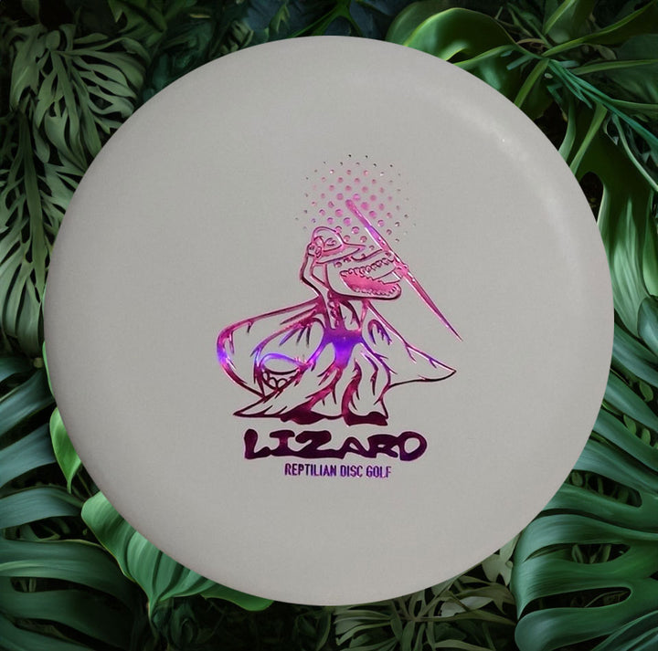 White Reptilian Wizard - FOSSIL disc golf disc with a holographic lizard design and "LIZARD REPTILIAN DISC GOLF" text on green leaves—ideal for Fossil Wizards and Reptilian fans.