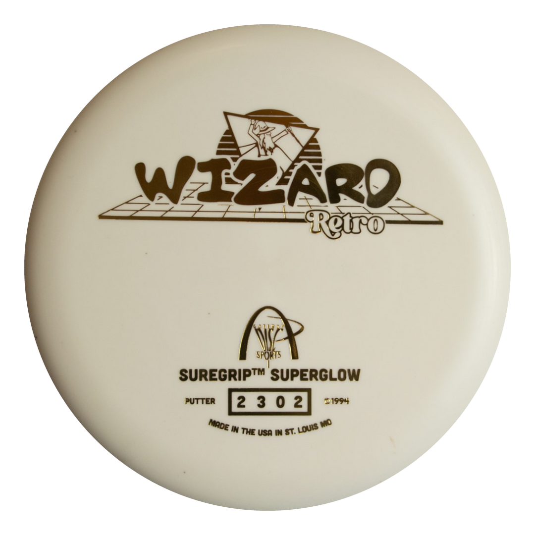 The Retro Wizard - SS Superglow is a white disc golf putter from the Retro series with "WIZARD Retro" and "SUREGRIP SUPERGLOW" printed in black, a wizard graphic, and manufacturer details. Made with Superglow formula for better nighttime play.