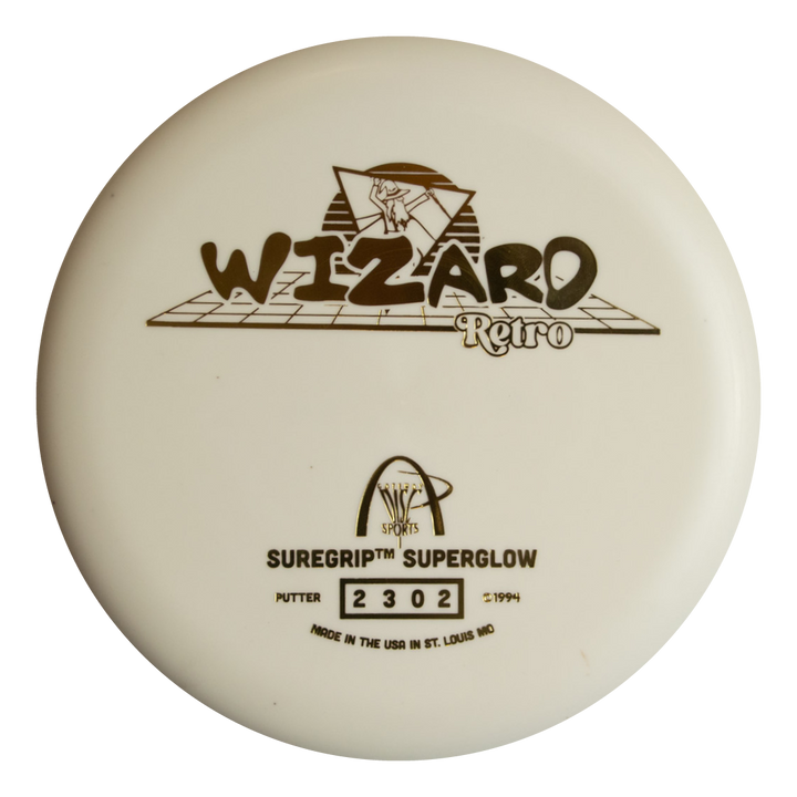 The Retro Wizard - SS Superglow is a white disc golf putter from the Retro series with "WIZARD Retro" and "SUREGRIP SUPERGLOW" printed in black, a wizard graphic, and manufacturer details. Made with Superglow formula for better nighttime play.