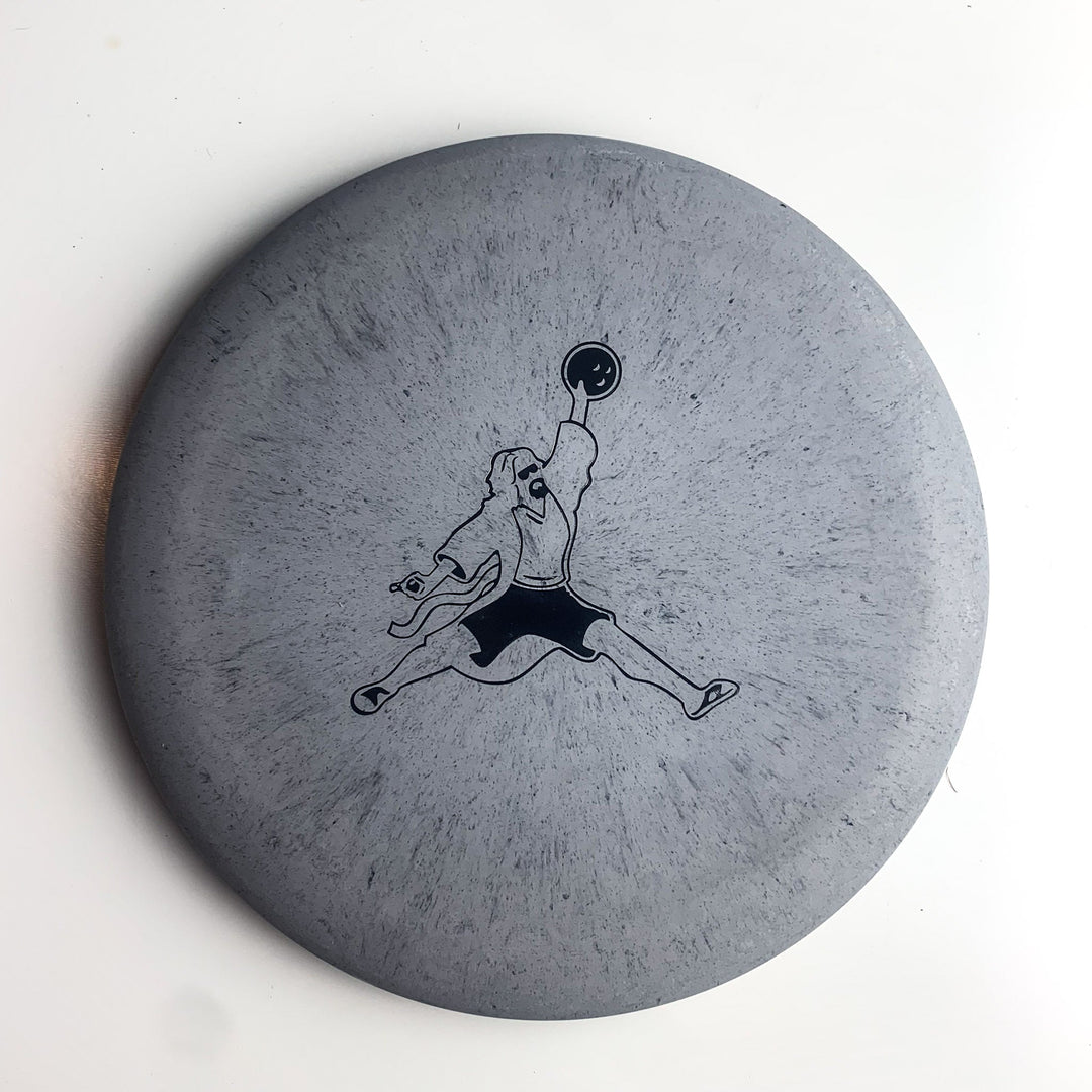 Gray disc with a black outline illustration of a person in mid-air holding a disc, mimicking the "Jumpman" pose—perfect for fans of Gateway Disc Sports putters. Product: Wizard Lunar - Air Dude. Plain white background.