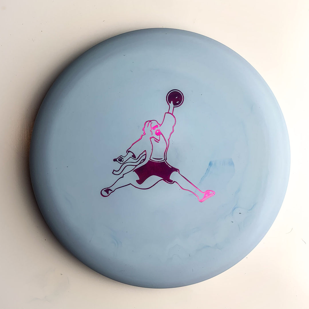 The Wizard Special Blend - Air Dude is a light blue disc golf putter featuring a purple and pink graphic of a person jumping and throwing a disc—ideal for fans of Gateway Disc Sports.