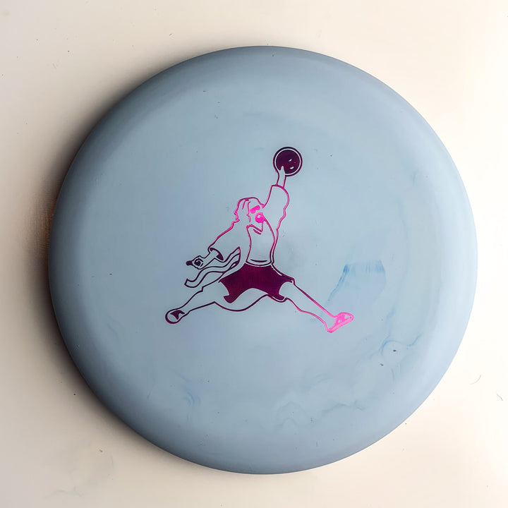The Wizard Special Blend - Air Dude is a light blue disc golf putter featuring a purple and pink graphic of a person jumping and throwing a disc—ideal for fans of Gateway Disc Sports.