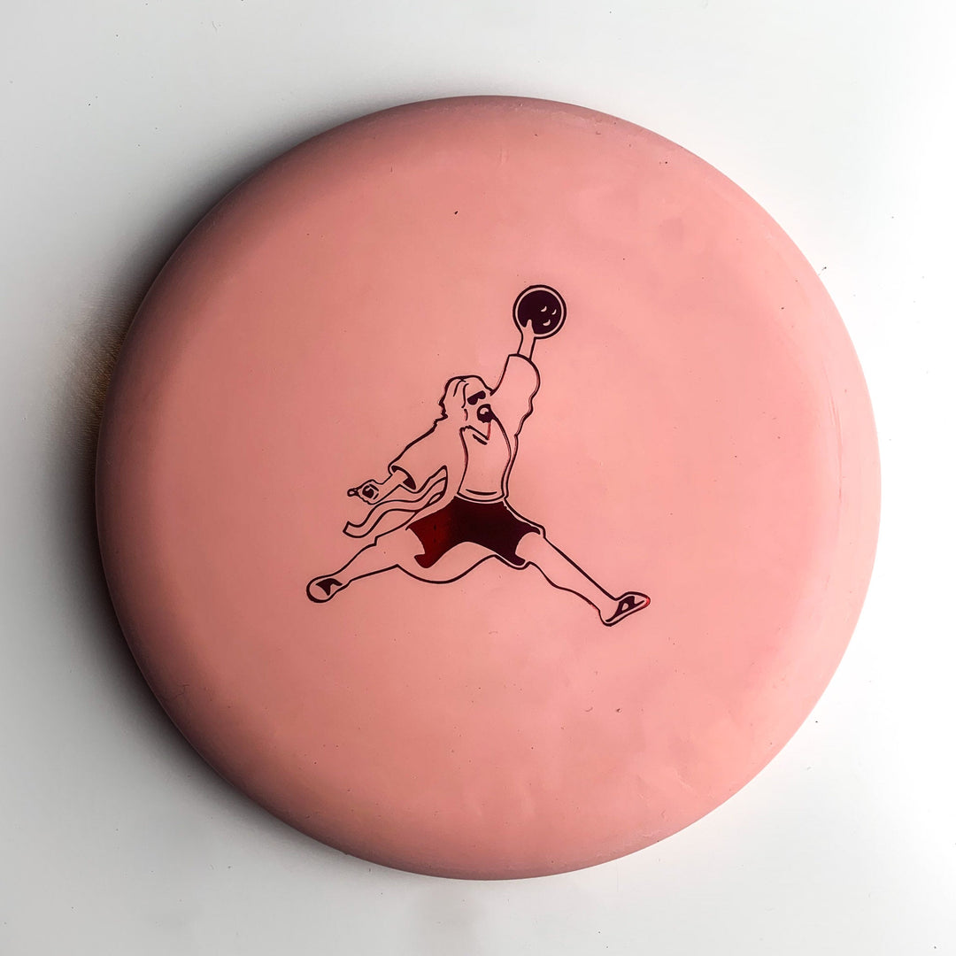 The Wizard Eraser - Air Dude is a pink disc golf disc featuring a black line drawing of an athletic person holding a disc overhead.