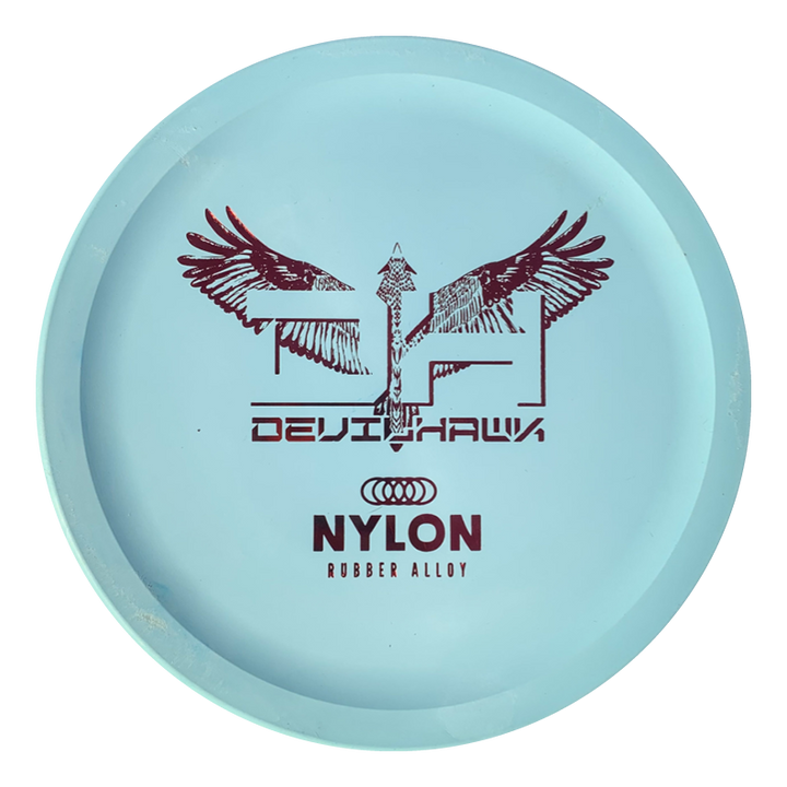 A light blue Devilhawk - Suregrip Nylon putt and approach disc with "DEVILHAWK" and "NYLON RUBBER ALLOY" in red, plus an abstract winged design and arrow.