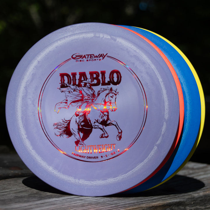 A stack of colorful Diablo Lightweight - SureGrip driver discs is displayed outdoors on a wooden surface.