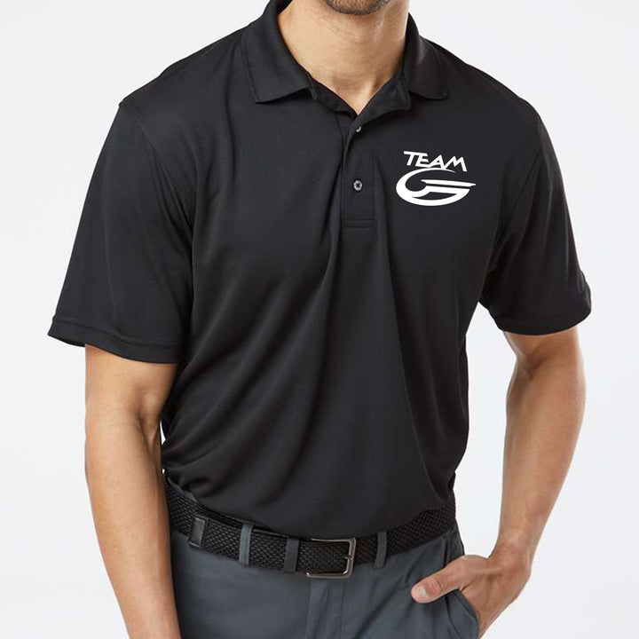 Man wearing a Black Team Gateway Polo with a white "TEAM G" logo on the left chest, featuring UPF 30+ sun protection, standing with one hand in his pocket.