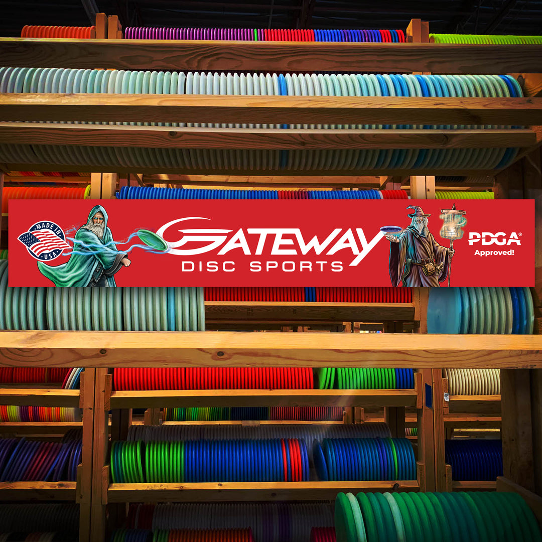 Shelves filled with colorful disc golf discs; a Gateway Disc Sports Banner, red with PDGA approval and Michael Barnard Illustrated Wizards, is displayed in the center.