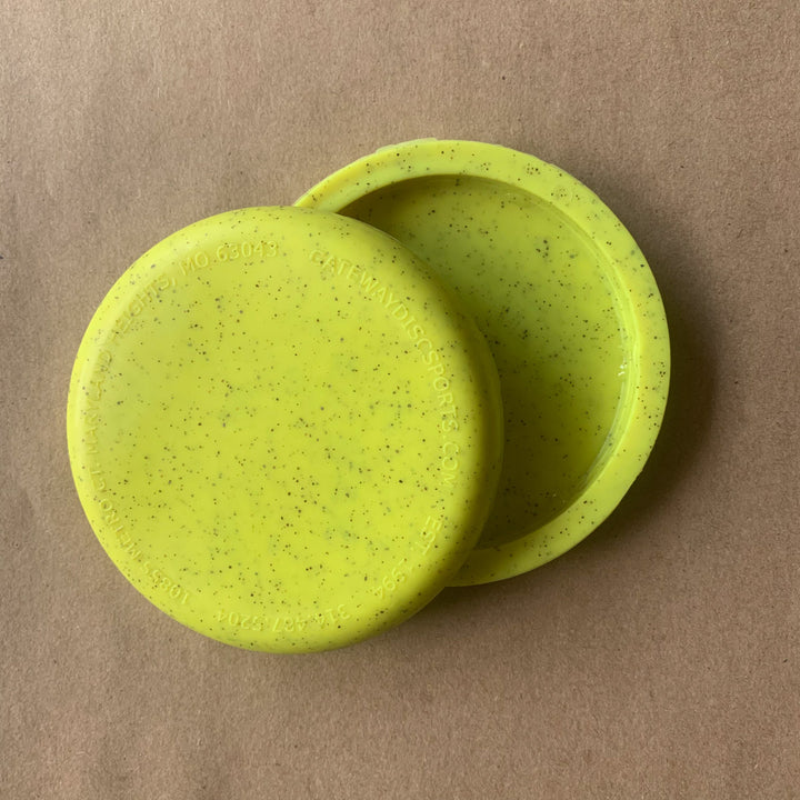 Two blank mini discs made from hemp, slightly overlapping on a plain brown surface—perfect for use as custom stamped mini markers or promotional giveaways. Product: Mini (Small) - Hemp - Blank.