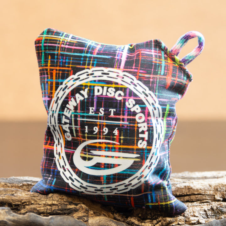 The Gateway Disc Sports x Jaybirdz Dry Bag is a colorful, handcrafted grip-enhancing chalk bag with —Gateway Disc Sports Est 1994—� and a chain ring design on the front, shown on a wooden surface.