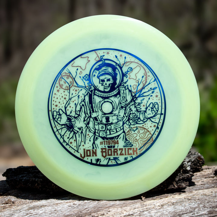A pale green Jon Borzick's Ether - Color Superglow distance driver by Gateway Disc Sports featuring a skeleton astronaut illustration, with "Jon Borzick" and #119794 printed below the artwork.