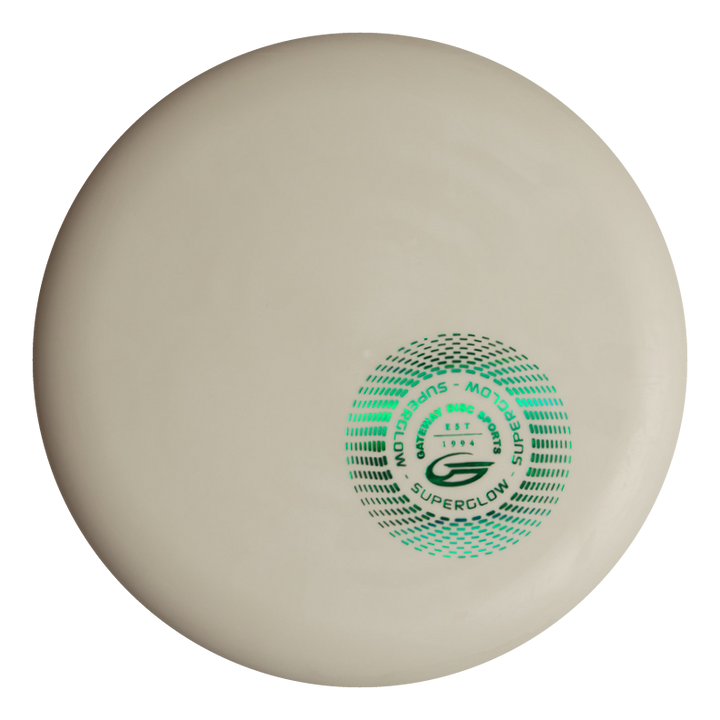 A white Magic - Suregrip Superglow - SS disc golf disc with green and black graphics in the center. This straight-flying disc offers easy control, making it ideal for players who want accuracy on the course.
