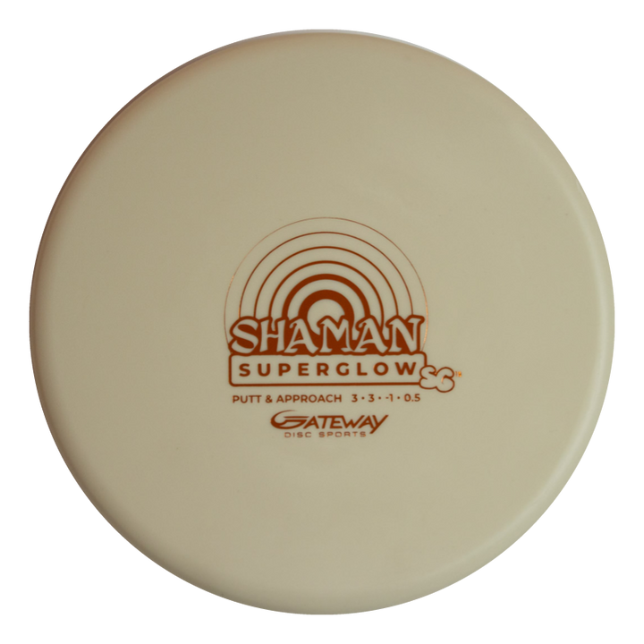 A cream-colored Shaman - SS - Suregrip Superglow putt and approach disc by Gateway Disc Sports, made from glow plastic with a brown rainbow graphic for enhanced visibility.