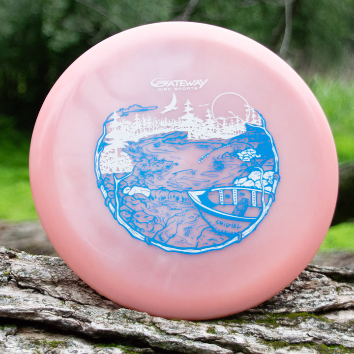 A pink Sam Smigiel's Element - NXT Color Superglow disc golf disc with great glide, featuring a blue and white river scene with a canoe, trees, and rocks, displayed outdoors on a tree trunk.
