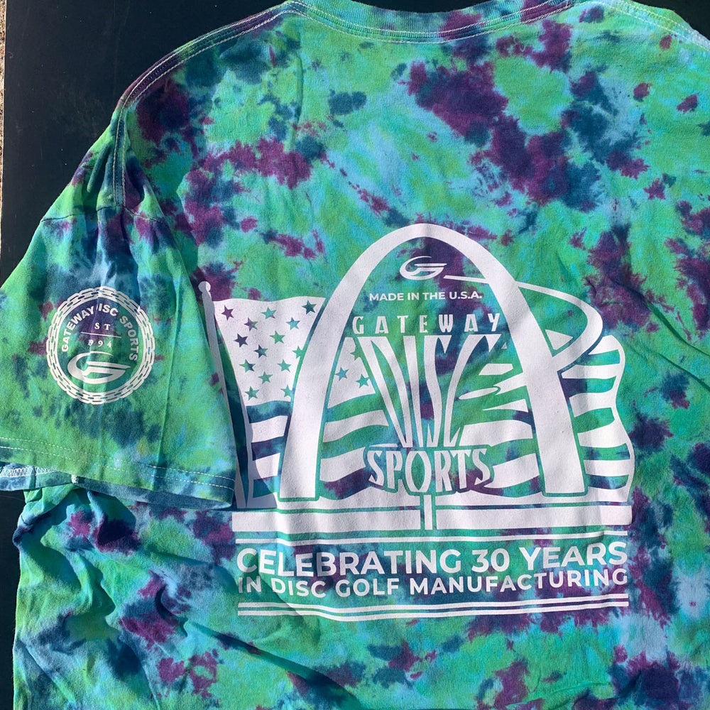 The 30th Anniversary - Tie Dyed T-Shirt is a hand-dyed cotton tee featuring the Gateway Disc Sports anniversary logo, arch artwork, and "Celebrating 30 Years in Disc Golf Manufacturing" text.