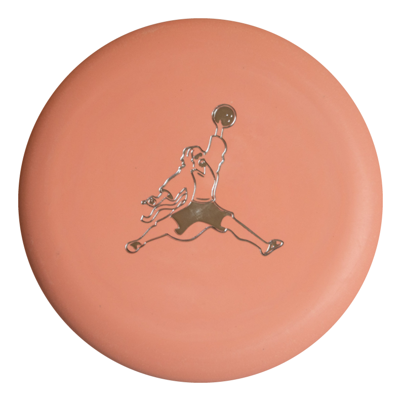 The Wizard Eraser - Air Dude is a round, peach-colored eraser featuring a metallic silhouette of Air Dude mid-jump, holding a ball overhead.