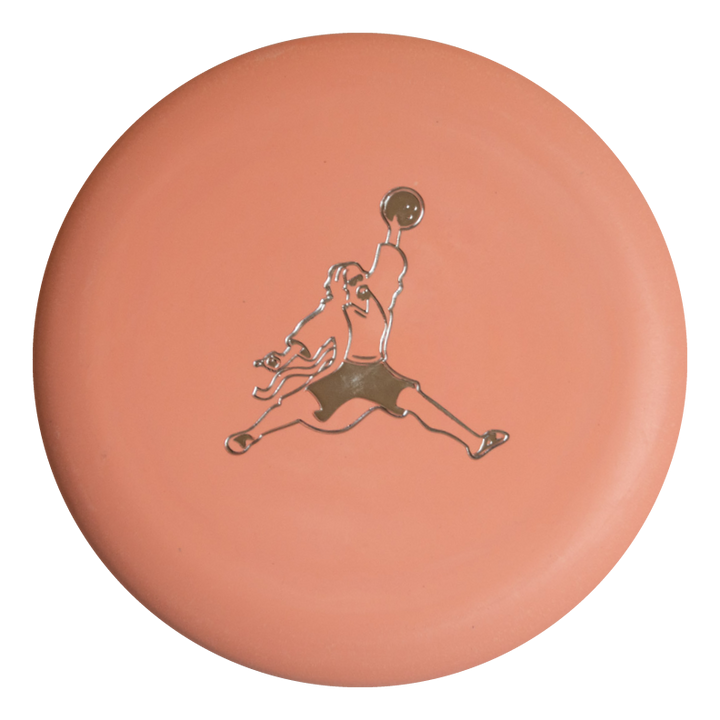 The Wizard Eraser - Air Dude is a round, peach-colored eraser featuring a metallic silhouette of Air Dude mid-jump, holding a ball overhead.