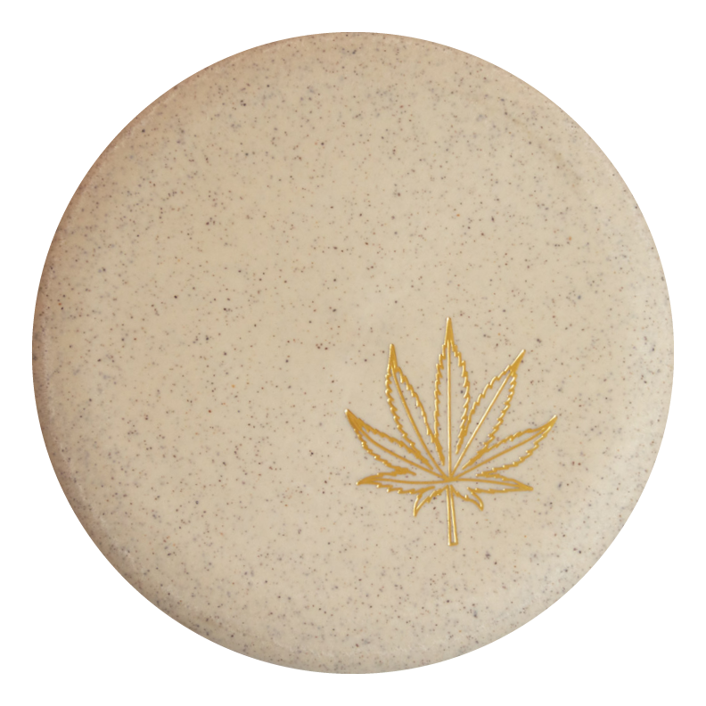 Round beige soap bar with small speckles and a gold cannabis leaf design, echoing the signature look of Wizard Leaf Suregrip Putters by Gateway Disc Sports.