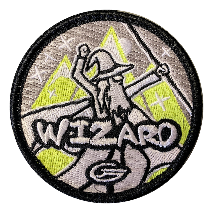 The Wizard Velcro Patch is a 3" circular patch with a bearded wizard raising his arms before mountain and star scenery, "WIZARD" embroidered below€”ideal for your Gateway Tour bag.