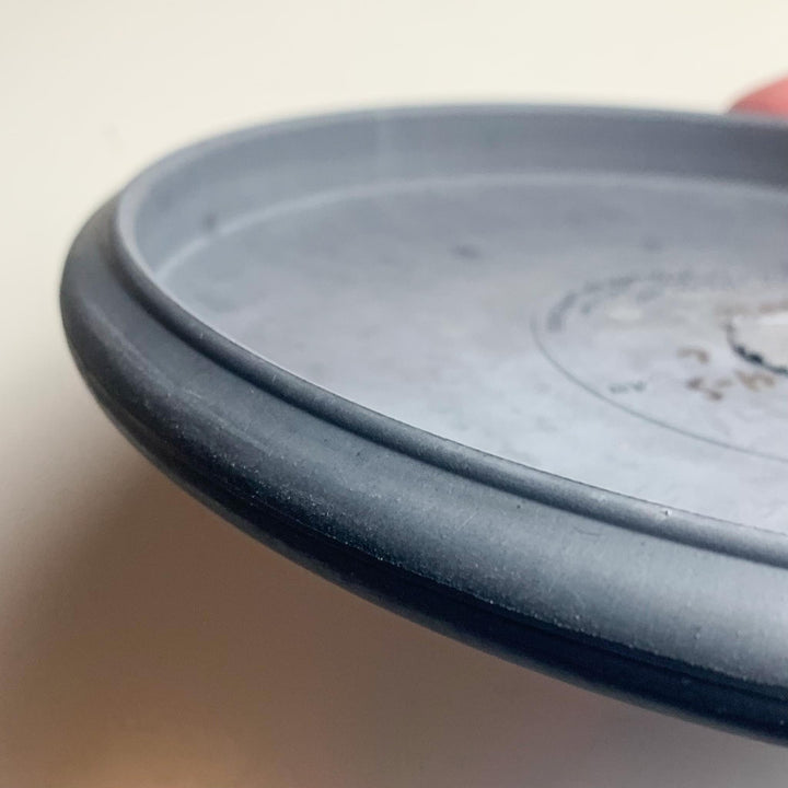 Close-up view of the rim and part of the top surface of a gray Wizard - SSSS putt and approach disc, featuring a beaded edge, against a plain background.