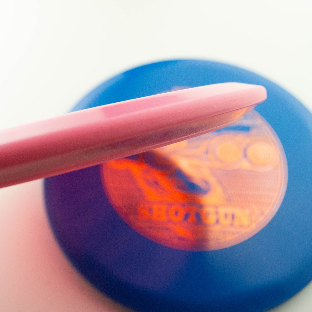 Close-up of the Black Zombie Shotgun — Platinum, featuring a pink disc resting on the edge of a blue disc with an orange "Hot Gun" logo.