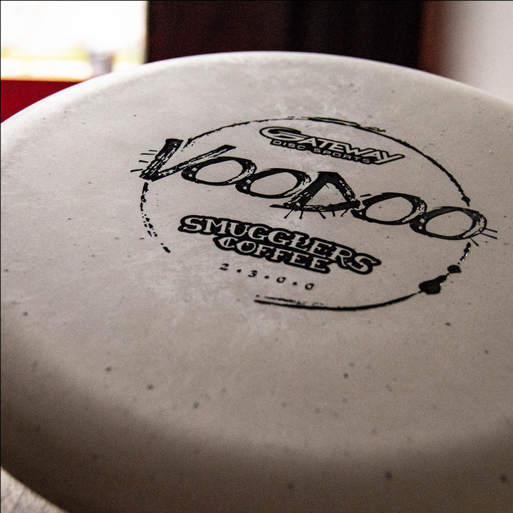 Close-up of the Voodoo - Smugglers Coffee Special Blend disc, featuring white plastic with Smugglers Coffee branding—perfect for disc golfers and coffee lovers celebrating a fresh espresso blend or coffee purchase.