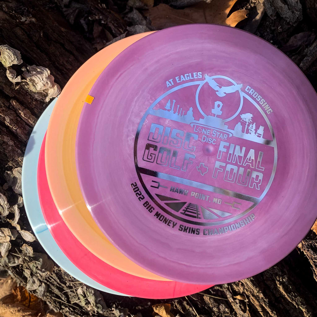 Four EC Lone Star - Chupacabra disc golf discs stacked on a tree trunk, with the top disc showing 2022 Skins Championship event details at Eagles Crossing in Hawk Point, MO.