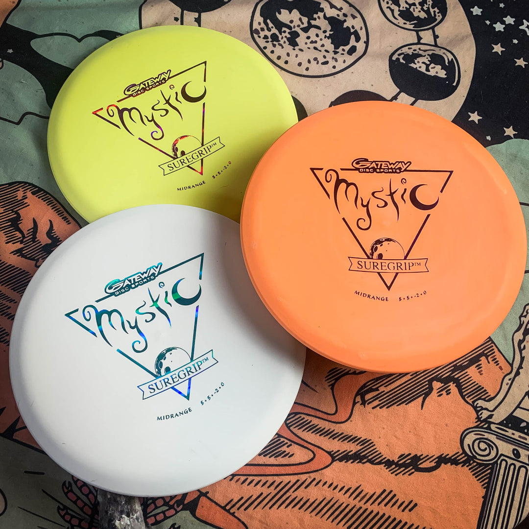 Three Mystic - SureGrip mid-range discs in yellow, orange, and white are displayed on a space-themed mat, ready for smooth straight flights with great glide.