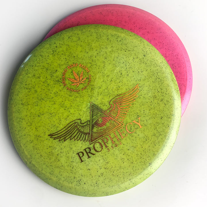 Showcasing our Prophecy - Diamond Hemp disc golf disc: a green overstable mid-range featuring a winged pyramid and "PROPHECY" text, overlapping a pink leaf-logo disc—both in premium Diamond blend—displayed on a white background.